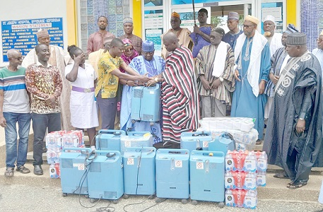 Nana Twumasi Darkwah (right), Gyasehene of New Juaben, being supported by Alhaji Mohammed Ashiru Issah Kurmi V (middle), Koforidua Zongo Chief, to present one of the oxygen concentrators to Dr Brother Samuel Worlasi Akoni (left), Medical Director of the St Joseph Hospital